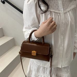 Retro dark brown leather handbag with gold metal lock for women, shown on shoulder