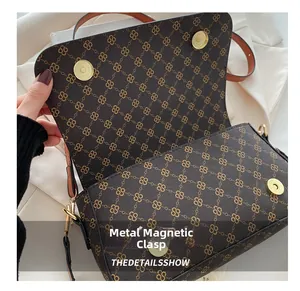 Detail shot of the gold magnetic snap closures on the dark brown patterned shoulder bag