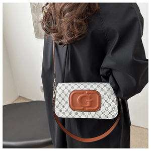 Detail of white canvas crossbody bag with G-embossed leather patch and chain print