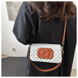 Detail of white crossbody bag featuring black chain pattern and leather G-embossed logo
