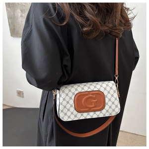 Detail of the white patterned crossbody bag with brown leather patch and embossed G logo