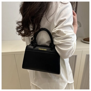 Detail view of black PU leather handbag with gold fashion lettering and stylish shoulder strap