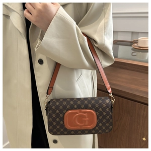 Detail of monogram shoulder bag featuring orange leather logo and gold hardware