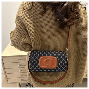 Close-up of printed canvas underarm bag with brown leather G logo and gold hardware detail