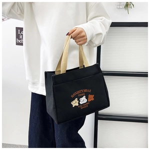 Detail of black canvas tote bag with naughty bear embroidery and thick beige handles