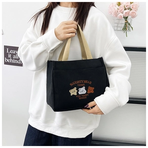 Detail of black canvas tote bag featuring cute bear embroidery and khaki web handles