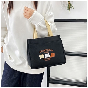 Close-up of black canvas tote bag featuring cute bear embroidery and cream handles