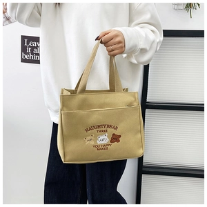 Detail of khaki canvas tote bag featuring cute bear embroidery and front zipper pocket