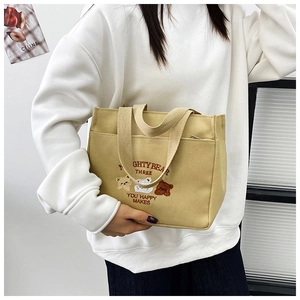 Detail of canvas tote bag featuring cute cartoon bear embroidery and Nighty Bear text