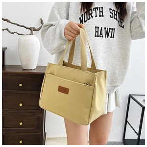 Detail of light yellow canvas tote bag with brown leather Sport patch and zipper pocket