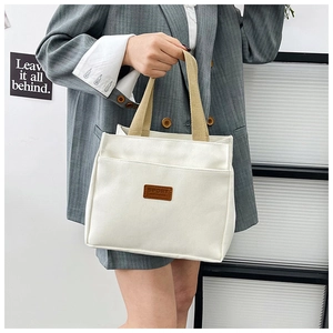 Detailed side view of white canvas tote bag with brown patch and sturdy fabric handle