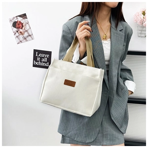 Side view of white canvas tote bag with khaki handles and sport leather patch detail
