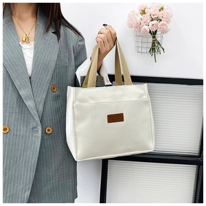 Close-up of canvas tote bag with brown SPORT leather tag and khaki strap detail