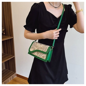 Detail of vintage style crossbody bag with green leather trim and Chinese wave patterns