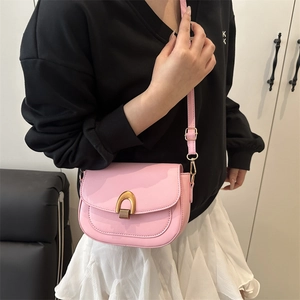 Bolso de hombro rosa minimalista con herrajes dorados mostrado en una modelo