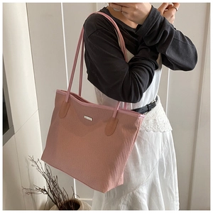 Detail of mauve woven tote bag showing the silver logo and brown leather strap reinforced joints