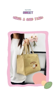 Detail shot of khaki canvas tote bag featuring cute teddy bear embroidery and webbed handles