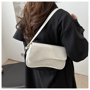 Close-up of white patent leather shoulder bag with a unique curved flap on a black coat