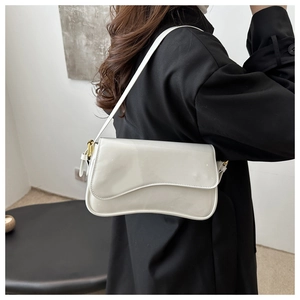 Détail du sac à bandoulière en cuir verni blanc avec rabat incurvé et boucle dorée