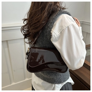 Vue latérale du sac à bandoulière en cuir verni marron foncé avec rabat ondulé