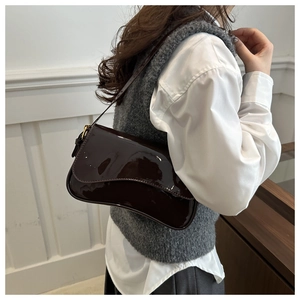 Détail d'un sac à bandoulière en cuir verni marron foncé avec finition brillante et boucle