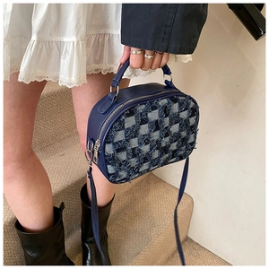 Dettaglio della borsa in tweed a quadri blu con trama a frange e finiture in metallo argento