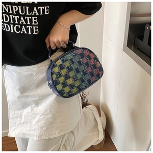 Detail of colorful plaid denim shoulder bag with frayed edges and metal zipper closure