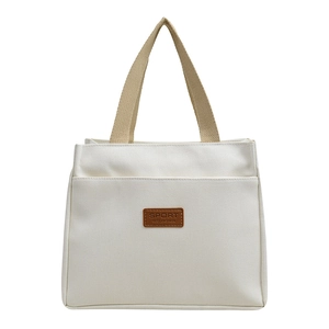 Chic beige canvas tote bag with brown leather label and stylish woven handles for women