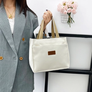 Minimalist canvas tote bag with brown straps and sport label shown in use