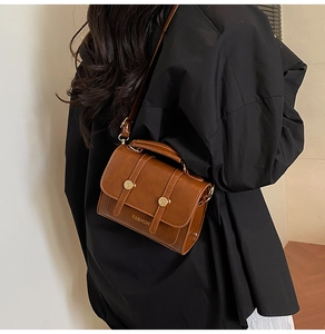 Brown retro crossbody bag worn by a model in a black shirt, showcasing scale and style
