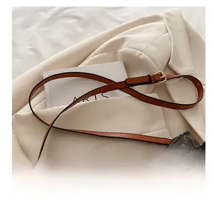 Detail of adjustable brown leather strap and gold hardware on retro patterned handbag