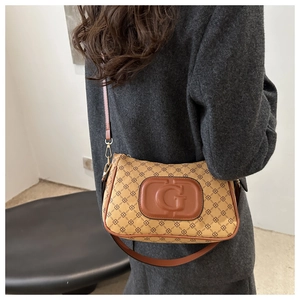 Detail of vintage underarm bag with embossed G logo and brown monogram pattern texture