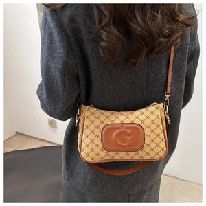 Detail of vintage patterned shoulder bag with leather trim and gold hardware accents