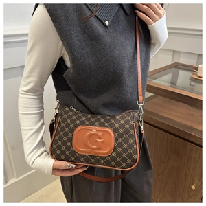 Detailed view of brown monogram crossbody bag with embossed G logo and golden hardware