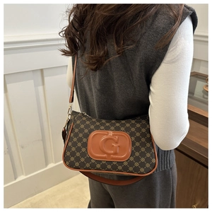 Detailed view of vintage shoulder bag featuring brown leather trim and embossed G logo