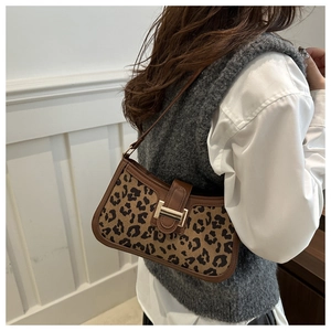 Détail d'un sac baguette léopard avec boucle dorée porté à l'épaule par un mannequin