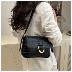 Détail du sac baguette noir texture croco avec boucle fer à cheval dorée à l'épaule