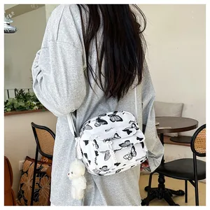 Detail of white nylon crossbody bag featuring black butterfly prints and bear charm