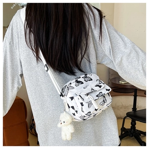 Rear view of a checkered nylon crossbody bag with black butterfly prints and bear charm