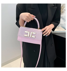 Detail of pink sequin shoulder bag with golden double E buckle held by a model