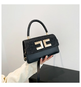 Macro detail of black sequined flap handbag featuring gold geometric metal logo clasp