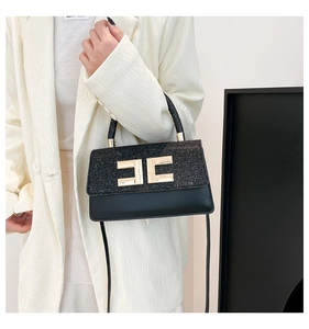 Detail of black crossbody bag with gold C-shaped metal clasp and glitter texture