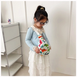 Toddler girl wearing a white dinosaur print chest bag with adjustable shoulder strap