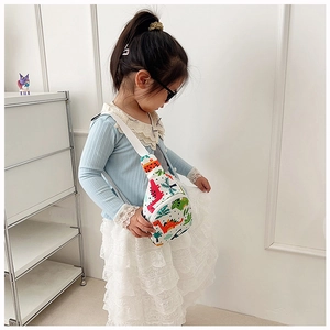 Toddler girl wearing white dinosaur chest bag in a bright minimalist setting