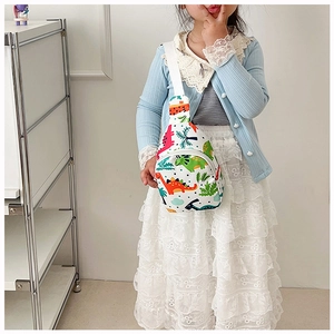 Detail of cute white dinosaur cartoon chest bag for toddlers worn by a small girl