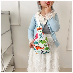 Toddler cartoon chest bag with dinosaur print worn by a little girl in a blue cardigan
