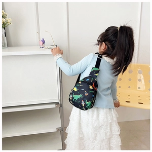 Detail of child wearing a black space-themed crossbody bag with dinosaur and rocket prints