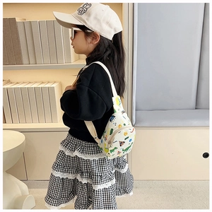 Toddler chest bag with cartoon dinosaur print worn by a child in a cozy indoor setting