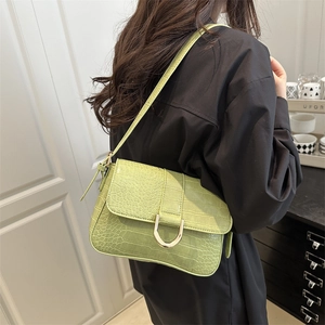 Sac baguette vert avocat texture crocodile avec boucle dorée en U porté par un mannequin