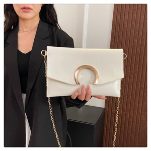 Close-up of a white envelope bag featuring a gold C-clasp and metallic chain strap